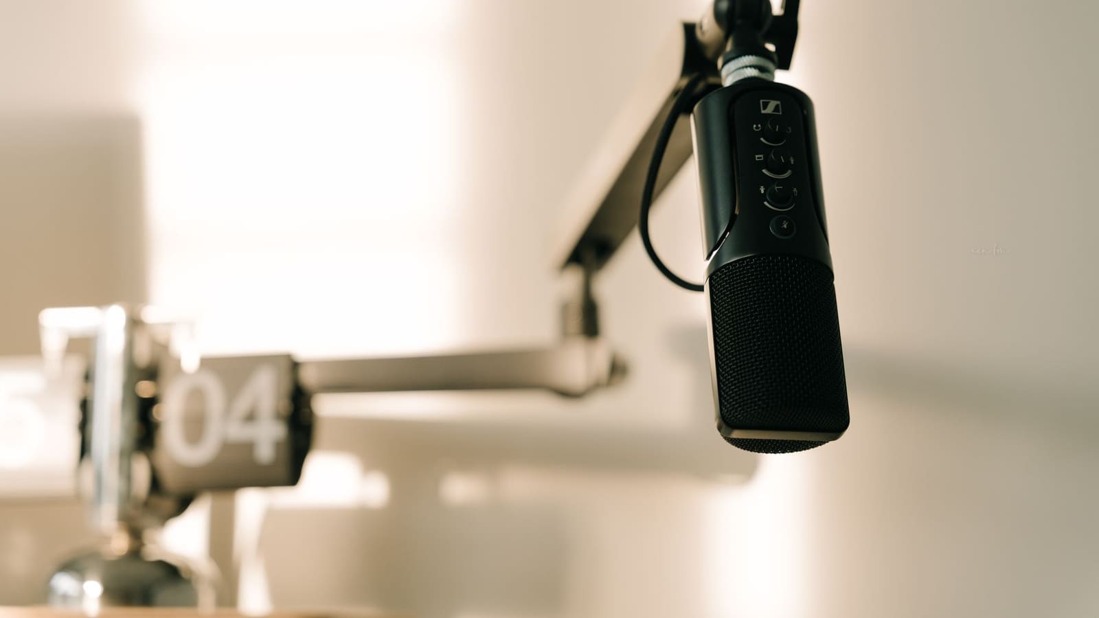 Abstract editorial illustration of a podcast microphone casting a shadow larger than a glowing television screen behind it, rendered in muted amber and deep teal tones